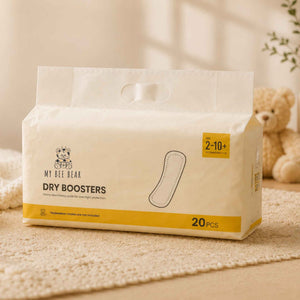 A package of My Bee Bear Dry Boosters hand towels, featuring a warm off-white design with yellow accents and a small teddy bear logo, set on a textured beige rug with a soft-focus teddy bear in the background.