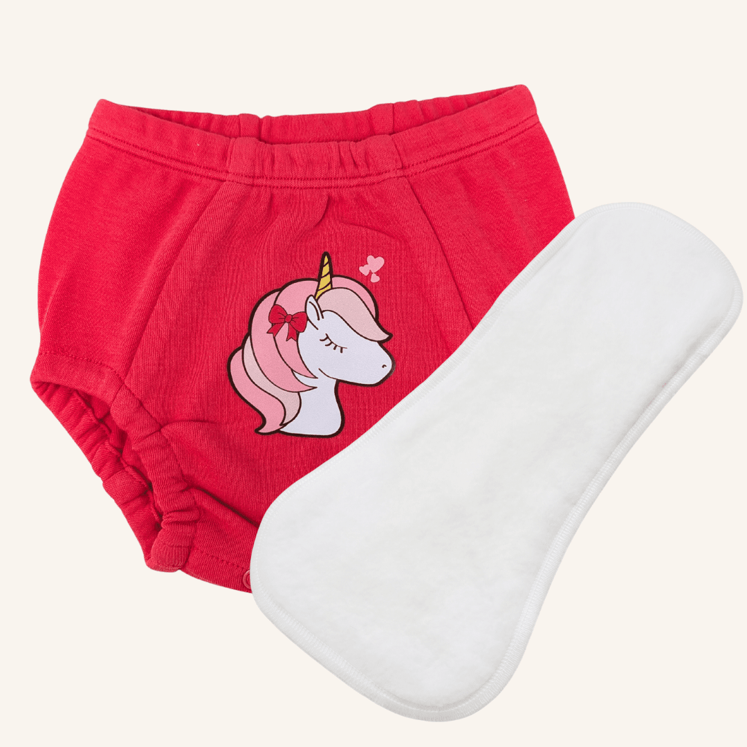 One pair of pink training underwear with unicorn design with white absorbent pad on a beige background 