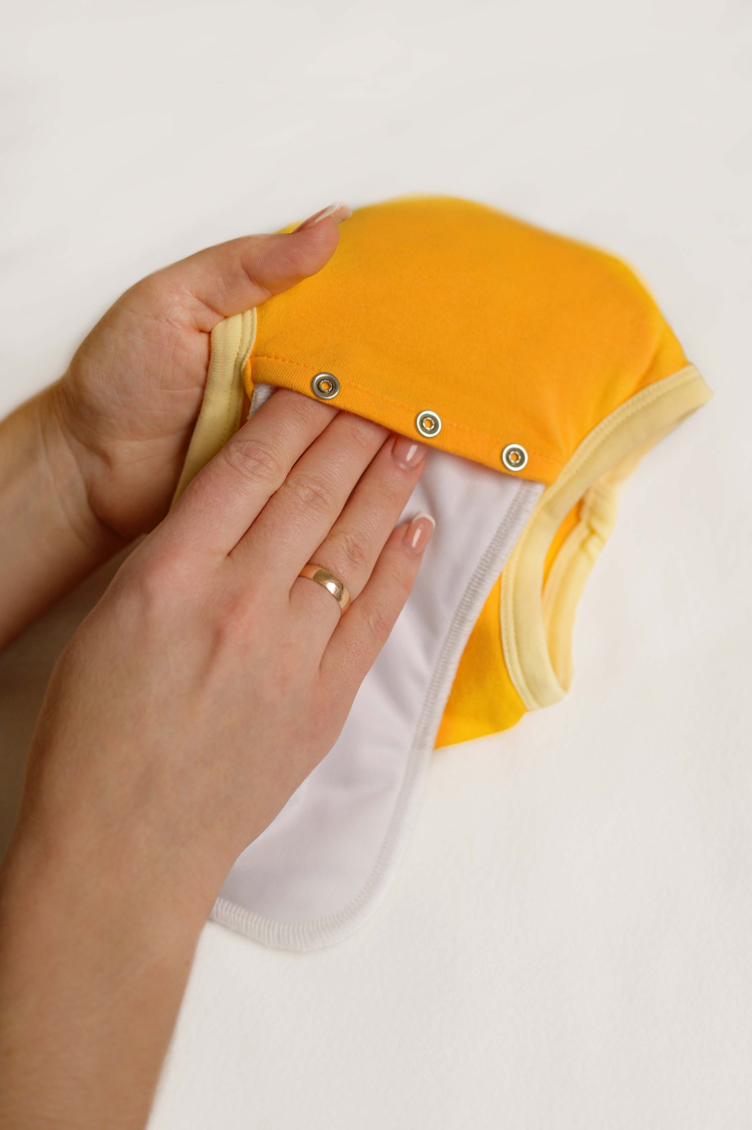 Yellow and white cloth underwear held by a hand on a light background